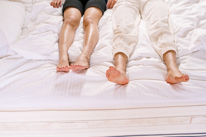 woman in black shorts lying in bed | hybrid mattress vs memory foam