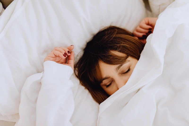 woman lying on bed covering her face with a white blanket | ipedic collection