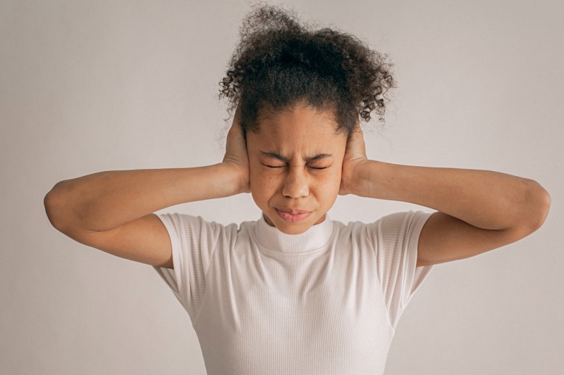 stressed black girl covering ears | earplugs