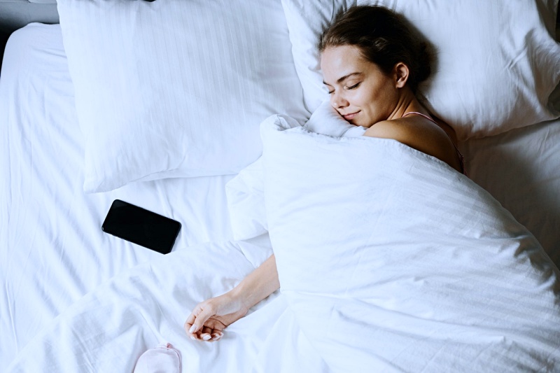 a woman sleeping beside her smartphone | how to wake up in the morning