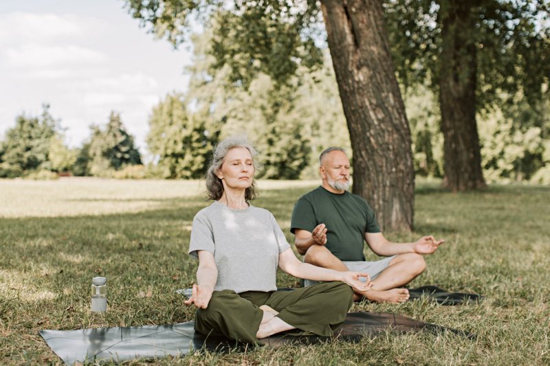 an elderly couple meditation in the park | how to improve sleep quality