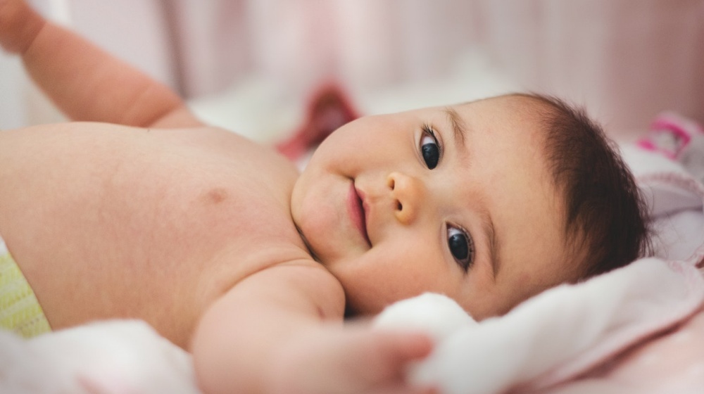 baby lying on pink bed | Baby's Sleep Pattern And Everything You Need To Know About It | Featured