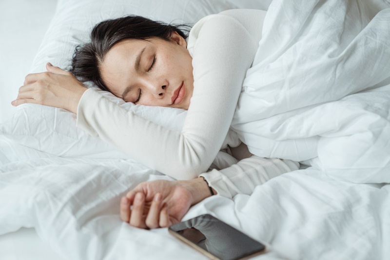 woman sleeping in bed near smartphone | sleep apnea