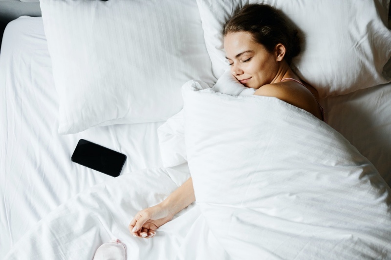 a woman sleeping beside her smartphone | Serta hotel mattress