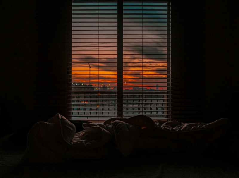 crumpled blanket in dark room at sunset | falling asleep