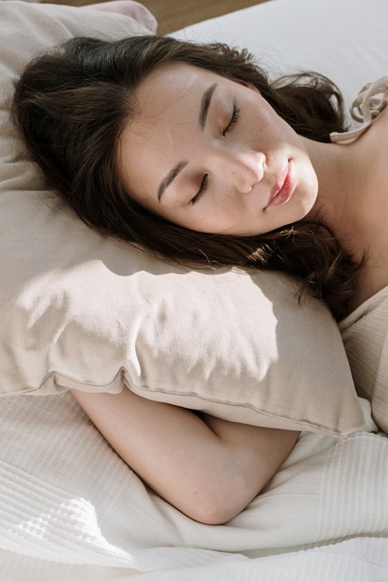 woman sleeping with pillow on bed | lack of sleep symptoms
