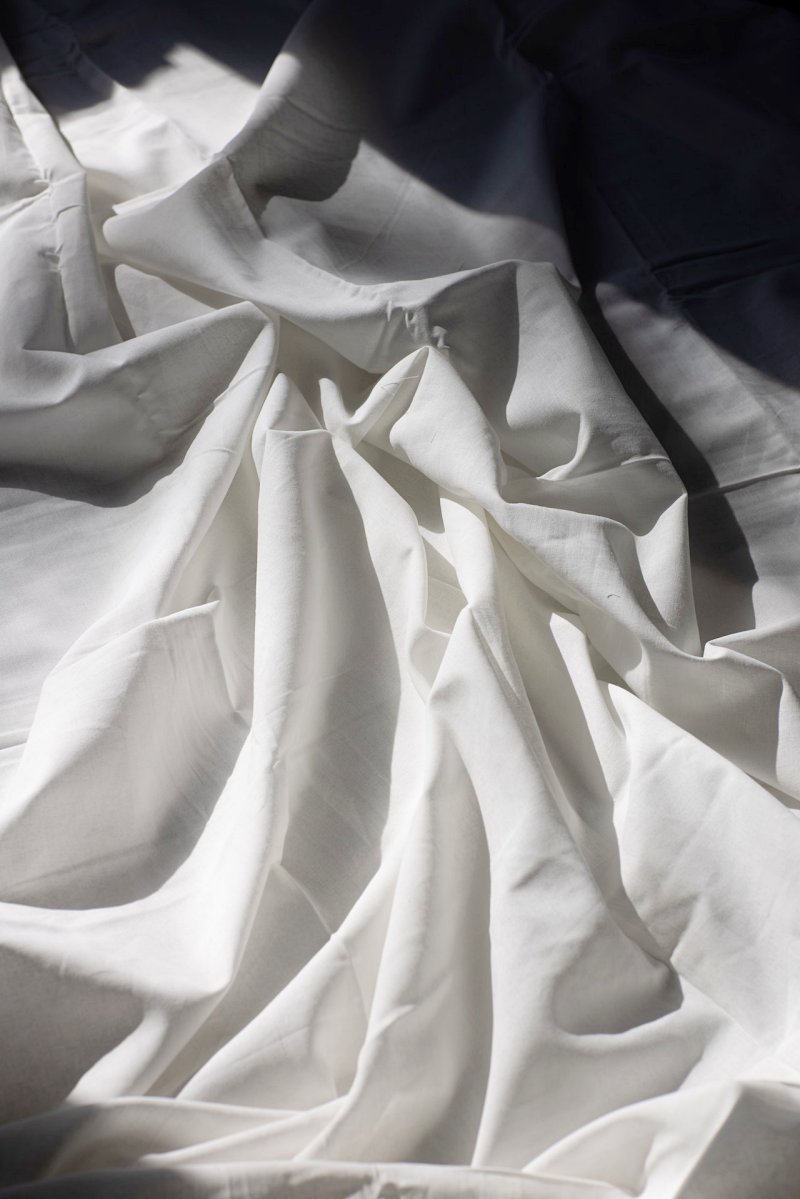 draped fabric on bed in sunlight | which bedsheet material is the best