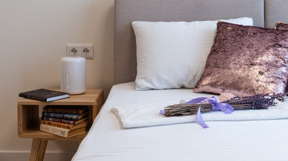 lavender bouquet placed on bed in cozy bedroom in sunny morning | Importance Of Fitted Bedsheets And Why Are They Must-Haves | Featured
