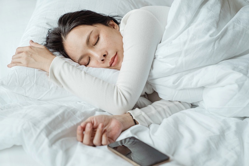 woman sleeping in bed near smartphone | bedtime