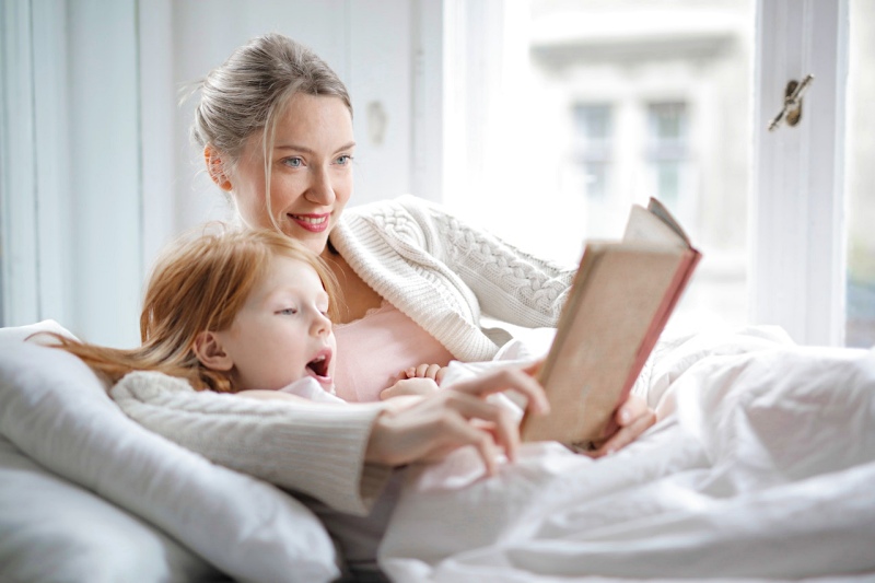 mother and daughter reading book with interest in bed | memory