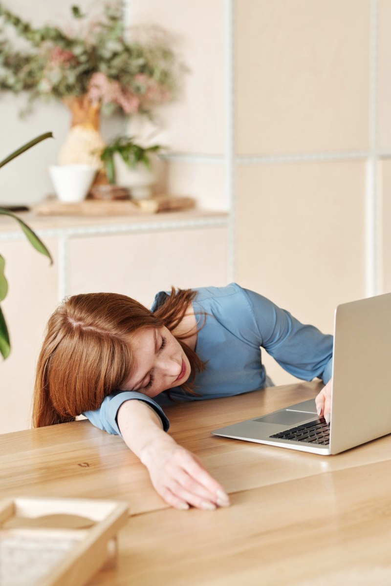 woman in blue long sleeve shirt using MacBook Air on brown wooden table | orthosomnia meaning