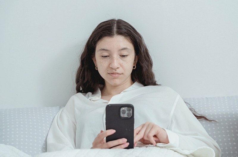 young woman using smartphone while resting on bed | quantified self