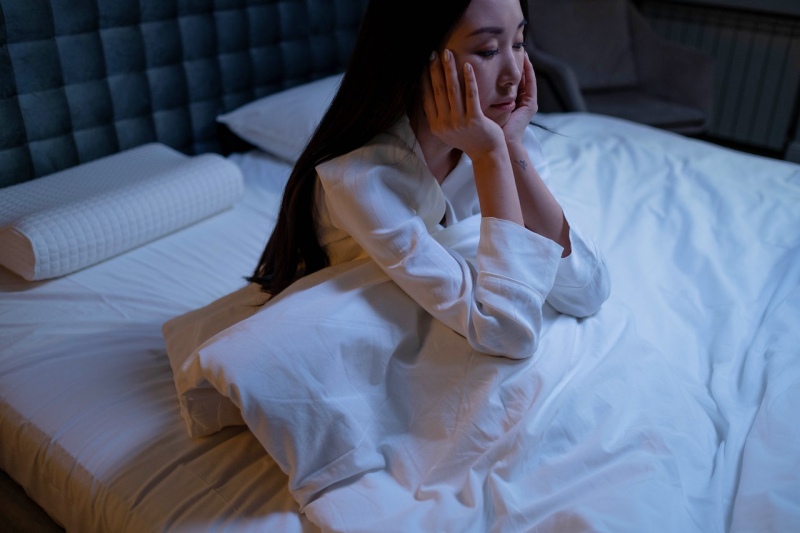 woman in white long sleeve shirt sitting on a bed | insomnia