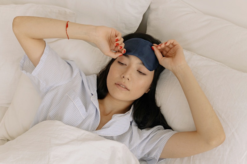 woman in a sleep mask waking up in her bed | Serta gel memory foam pillow