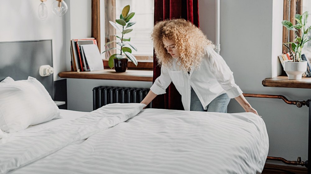 woman in white long sleeve shirt sitting on bed | Bedroom Allergens: How Effective Are Hypoallergenic Beddings | Featured