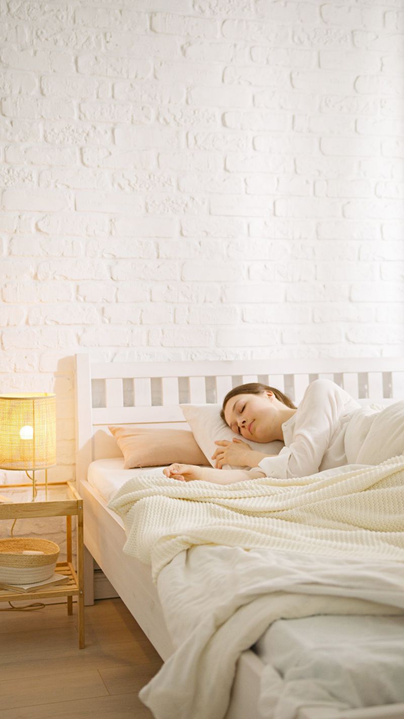 a woman sleeping on her bed beside a lamp | orthopedic mattresses