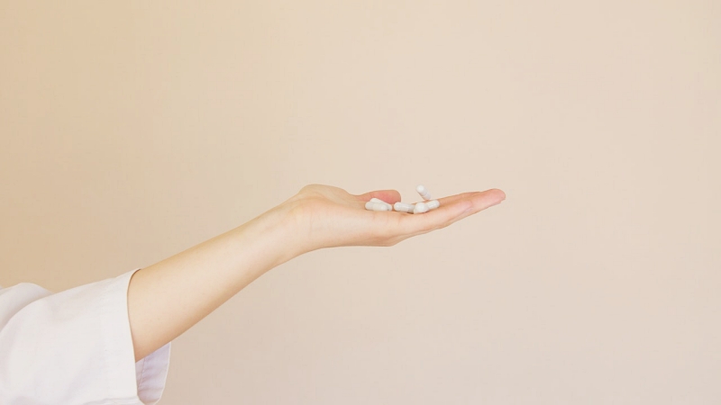 crop female pharmacist with pile of white pills on palm | herbs to aid sleep