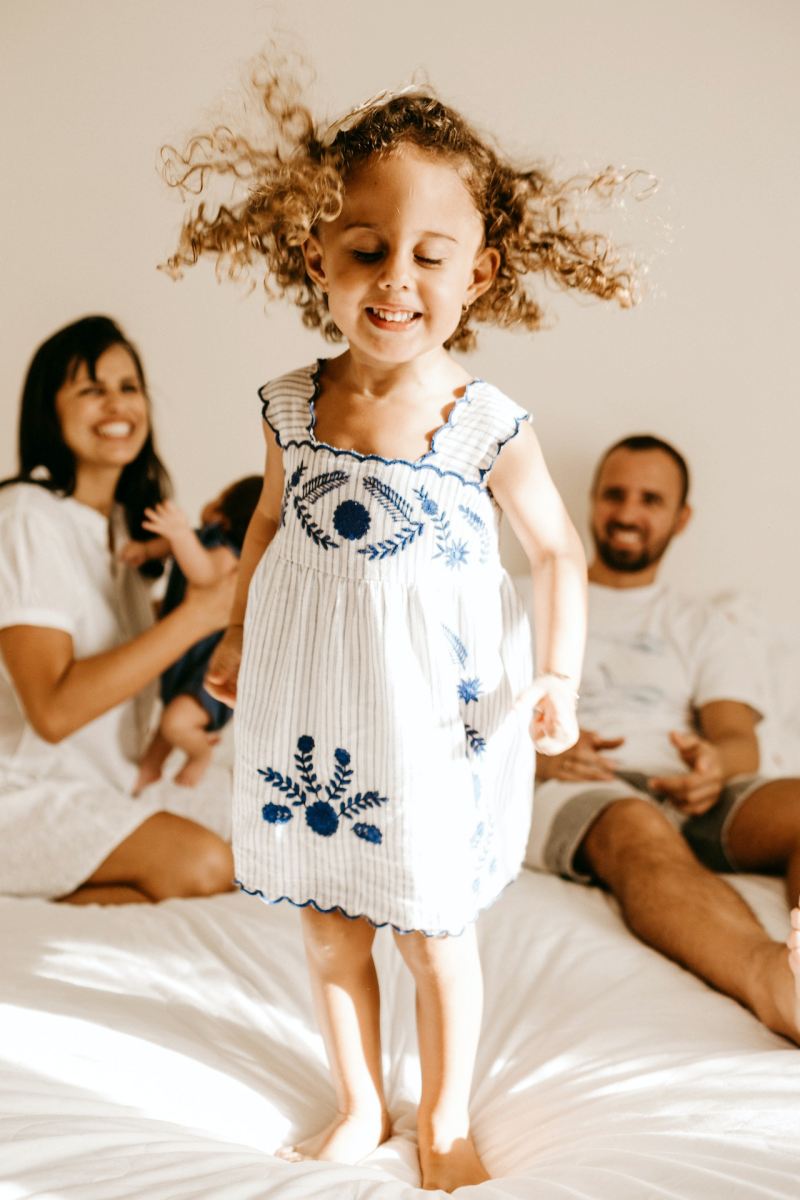 happy little kid having fun on bed with cheerful parents | toddler mattresses