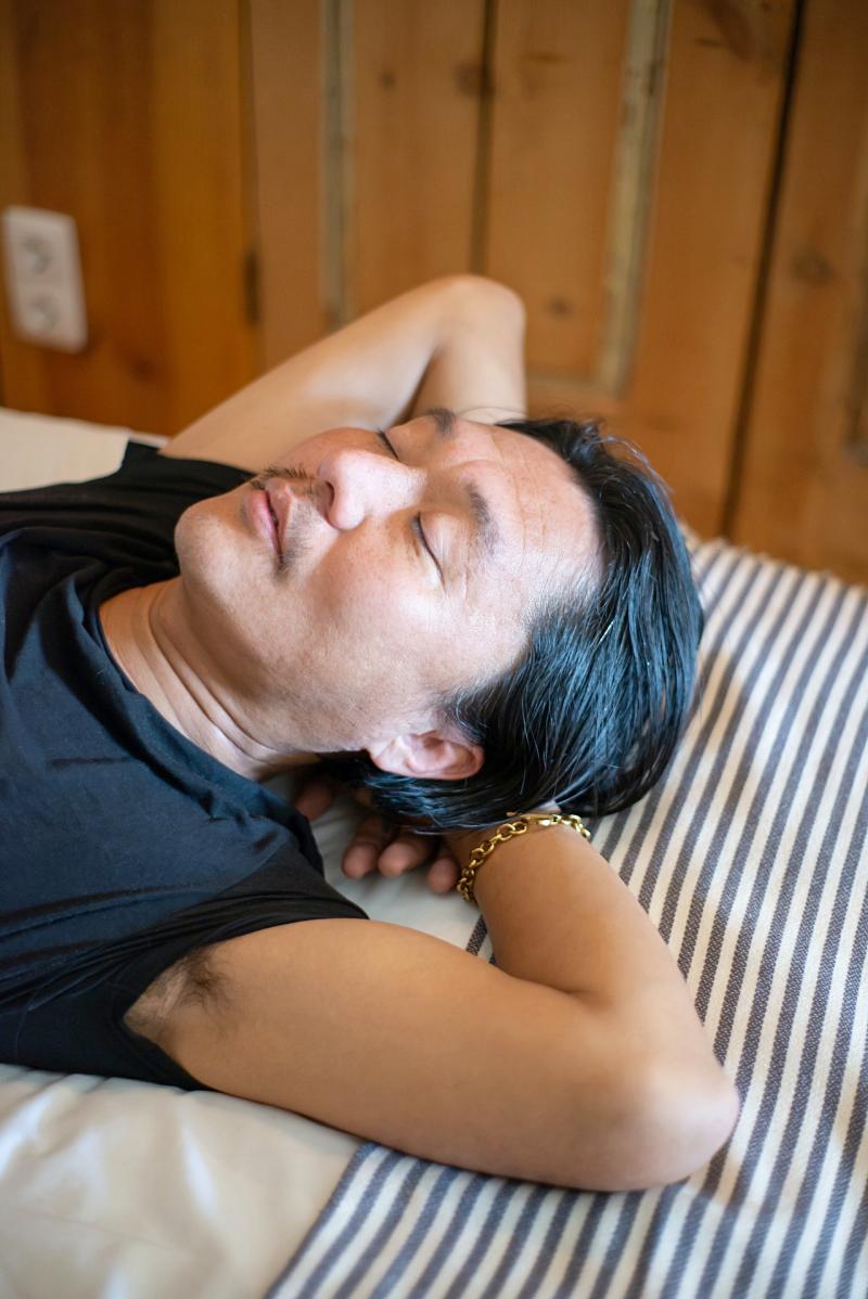 close up photo of a man in a a black shirt sleeping | best mattresses for sleep apnea