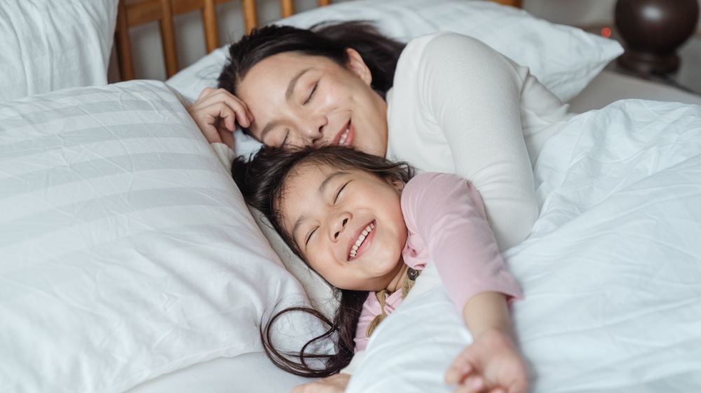 cheerful mother and daughter resting in bed | mattress investment