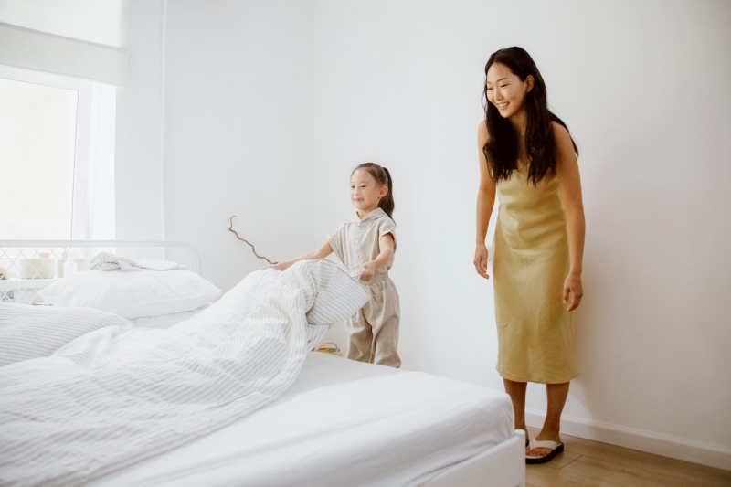 daughter making a bed and mother looking at her | how to clean serta mattress