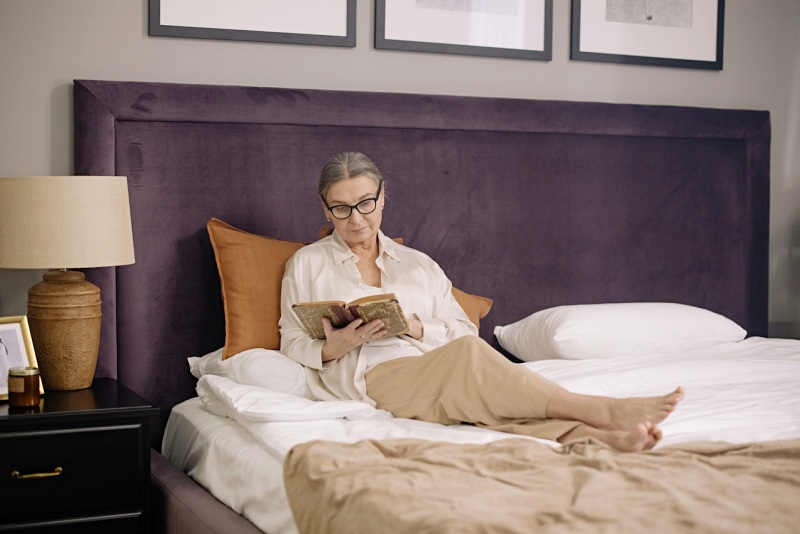elderly woman sitting on bed while reading a book | mattress for seniors